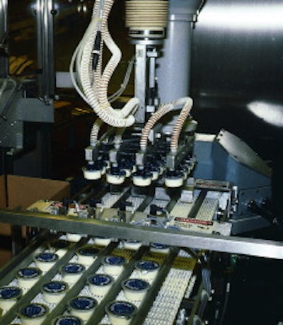 On the 2-oz line, the robotic head prepares to place 20 cups into a waiting case. To the left of the head is a sheet inserter th