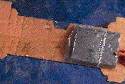 The flat blank is folded in half down the center, loosening the plastic sleeve enough to permit the computer to be tucked inside