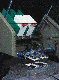 An automatic card feeder places cards face down over the formed and filled blisters