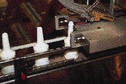 Cap feeder delivers caps to capper, which has a removable brass chute end (inset) dedicated to each cap size. No tools are neede