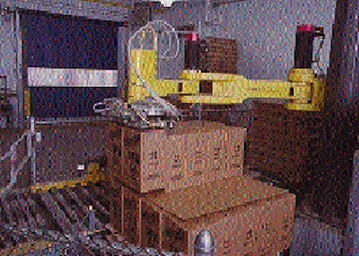 A robotic arm (top) transfers two of the heavy cases from the conveyor and onto a pallet load. The robot will soon be building t