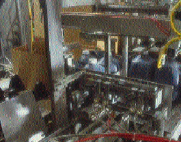 In the packer, four jugs are being pushed onto the case blank before it?s folded and glued