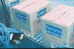 Cases of aerosol products are conveyed to the labeler (top) where bar-coded labels are printed then applied using the tamp-blow