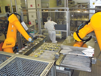 DOUBLE DUTY. Two robots work together to handle filled bags of parenteralia, as well as empty and filled trays of product bound