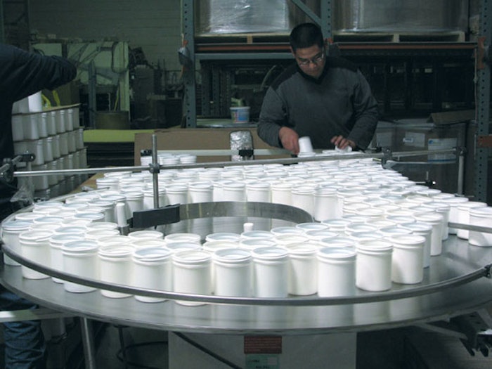 CREATING ORDER. One project, for a powdered household cleanser, begins on APCO Packaging's U-shaped packaging line with manual d