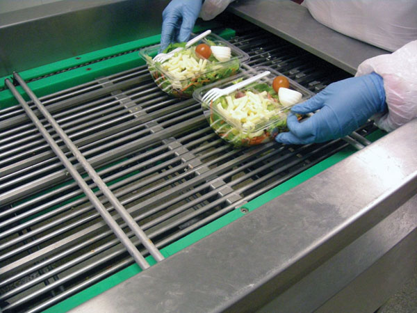 HANDY PACKAGING. An operator places prepared salads in rPET containers two-up at the infeed (above) of the Hera MAP system, also