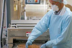 HAND LOADING. Meat portions are loaded by hand shortly after the forming web leaves the thermoforming station.