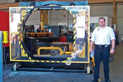 WRAP MASTER. Machine shop manager Joe McKenna stands beside the 87' semi-automatic orbital stretch wrapper.