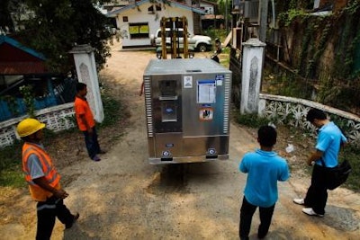 A flu vaccine shipment in a temperature-controlled container is moved by a team in Laos.
