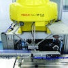 A high-speed delta robot uses a vacuum end-of-arm tool to pick up individual diagnostic test kits and feed them to a flow wrapper.
