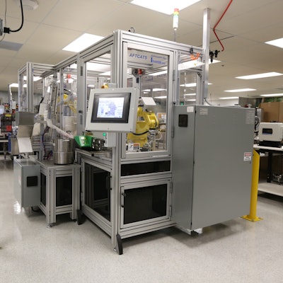 The front of the AFTCATS robotic bottling system shows the main touchscreen display, with the pick-and-place loading robot shown in the window.