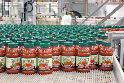 Pasta sauce bottles enter a labeler at left, then exit labeled at right. Filled, capped, and labeled bottles accumulate on a high-speed bottling line at LiDestri’s Rochester, NY, facility.