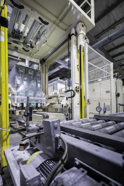 Conveyor transports the stacks to the packaging system, where a film hood is pulled over the palletized beverage cases.