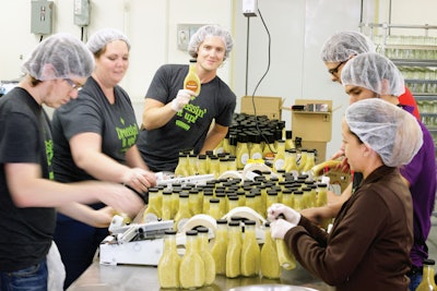 CLOSE WORK CEO. Richard Hanley (center) fills the bottles via semi-automatic hydraulic filler.