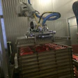 MULTIFUNCTION EOAT. The robot not only picks and places lay-flat flexible pouches into the stainless-steel trays, but it also transfers empty trays onto the stack for filling.