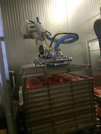 MULTIFUNCTION EOAT. The robot not only picks and places lay-flat flexible pouches into the stainless-steel trays, but it also transfers empty trays onto the stack for filling.