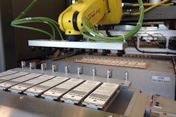PACK UNLOADING. On the 100-pack/min line, finished blister packs are removed from the blister-sealing machine via a ceiling-mounted robot and are placed in front of sensors for inspection.