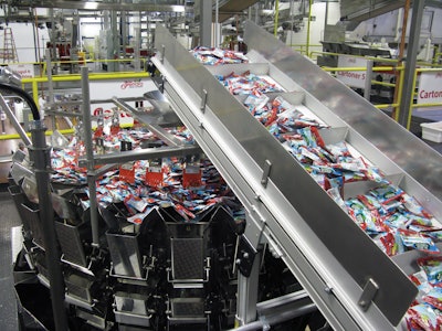 BAGGER, CARTONER. Pouches of fruit snacks move through a combination scale.