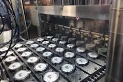 HOT-FILLED CUPS. Once cups emerge from hot-filling and lidding, they’re encased in paperboard sleeves and then robotically placed in corrugated trays.