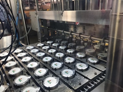 HOT-FILLED CUPS. Once cups emerge from hot-filling and lidding, they’re encased in paperboard sleeves and then robotically placed in corrugated trays.