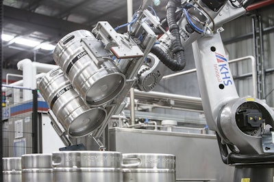 Kegs are turned by the robot and placed on a conveyor leading to the keg washer.