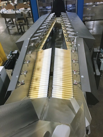 Shown here is one of 12 automated feeding systems. Including both left and right sides, each feeding system deploys 180 rollers in clusters of six. Each cluster has its own sensor, its own stepper motor/drive combo, and its own controller. Because each cluster communicates with the ones around it, each controller knows if the overall goal of singulating the flow of pouches will be better accomplished by speeding up or slowing down its six rollers.