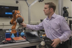 NIST engineer Jeremy Marvel adjusts a robotic arm used to study human-robot interactions. Photo courtesy of F. Webber/ NIST.