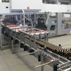 Shortly after freshly filled bottles enter the Varioline packing system, they’re picked and placed into cases that have six-pack paperboard carriers already in them.