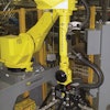 Near the end of the line, one robot forms pallet layers by using its compression gripper to move pairs of packs around on the conveyor.