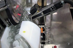 Paired timing screws partially invert bottles so their bottoms can be imprinted by the CIJ coder.