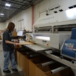An operator in the bulk area glues the side of a case blank.