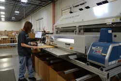 An operator in the bulk area glues the side of a case blank.