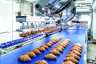 A two-axis robot gently picks filled croissants from the transport module and places them back onto a conveyor.