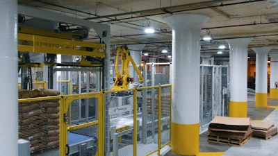 A robotic bag palletizer creates perfectly uniform stacks of bags on a pallet, which then receives a stretch hood.
