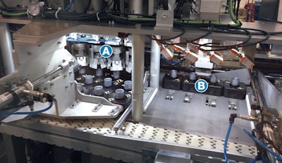 Closure Subassemblies—each in a puck and each already filled with liquid amplifier—enter the Nuspark system and are immediately pushed from a white conveyor belt and into a station where four mechanical grippers (A in photo) orient them four at a time. The pucks are then pushed to the next position (B in photo), where four Casing Subassemblies come down from above and are placed in the four Closure Subassemblies. Then the four pucks are pushed back onto the white conveyor belt, which takes them to the next station.