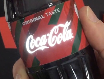 Printed electronics technology causes the Coca-Cola logo to light up at the touch of the hand.
