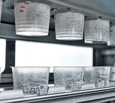 The denester puts in-mold-labeled soup cups onto the walking beam infeed conveyor.