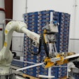 A six-axis articulated robot applies corner boards to the four edges of the pallet, after which it is stretch wrapped.