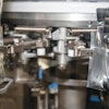 Pre-labeled pouches, seen here from their transparent backs, are being opened and filled in the GP-M3000 before being vibrated to settle the buds, then heat-sealed.