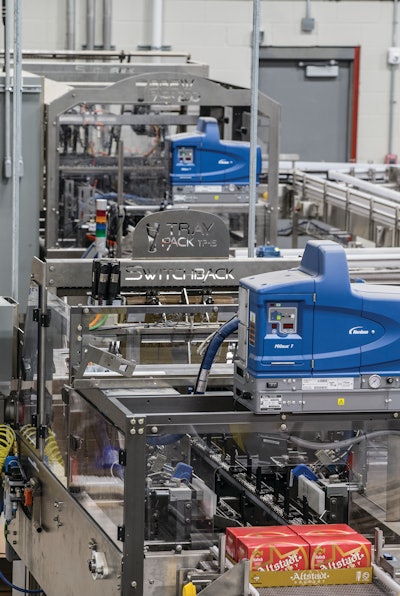 Near the end of the new canning line sits a tray packer that receives six-count cartons from an upstream cartoner and packs them into corrugated trays four per tray.