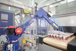 This robot picks freshly printed cans six at a time from the vacuum conveyor discharge and places them on the infeed conveyor of the curing oven.