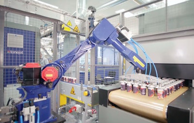 This robot picks freshly printed cans six at a time from the vacuum conveyor discharge and places them on the infeed conveyor of the curing oven.