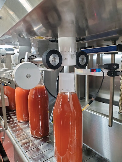 Neck label being applied by the shrink-sleeve labeler.