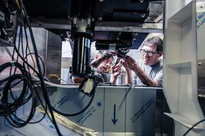 All-Fill employees work on the inside of a bulk hopper that feeds a PB Series bottle unscrambler.
