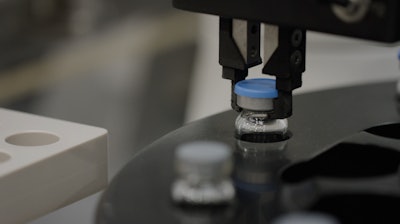 A robotic arm prepares to place a finished vial back into the nest.