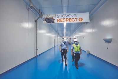 Plant workers travel through pristine corridors that display company values, such as showing respect and winning together.