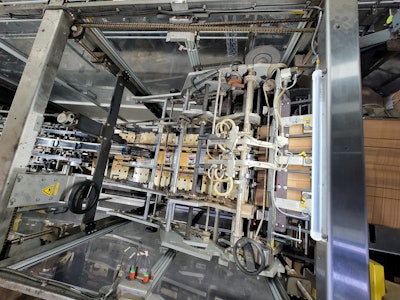 An overhead view and a side view illustrate how printed paperboard cartons are indexed out to cover, then enclose the two parallel lanes at a depth of three cans, creating the 2x3 six-pack format. No glue is required in the operation.