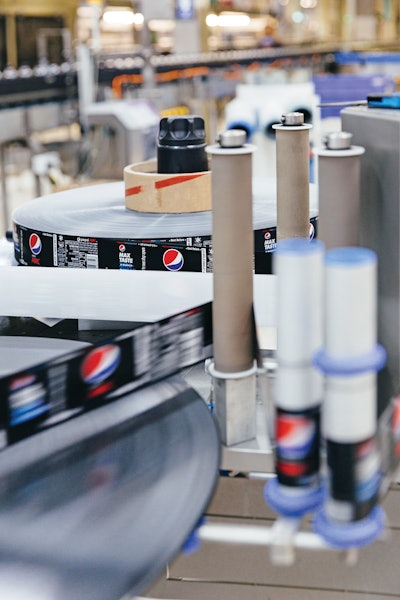 Bottles filled with sugar-free Pepsi Max are dressed with their characteristic black labels on the roll-fed labeler.