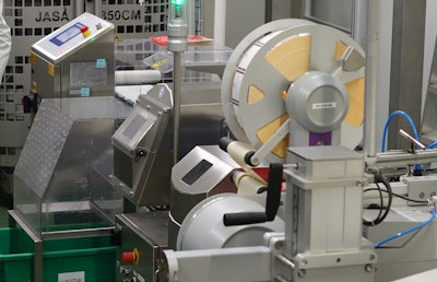 The label printer/applicator uses one size label with a preprinted border; product details are printed in-line in the required language.