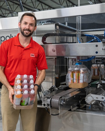 The Unwrapper machine (background) automating the removal of shrink film from corrugated beverage trays. Chris Harris, (foreground) North American Sales Division Manager at Polypack, holding the end-product, a beverage multipack.